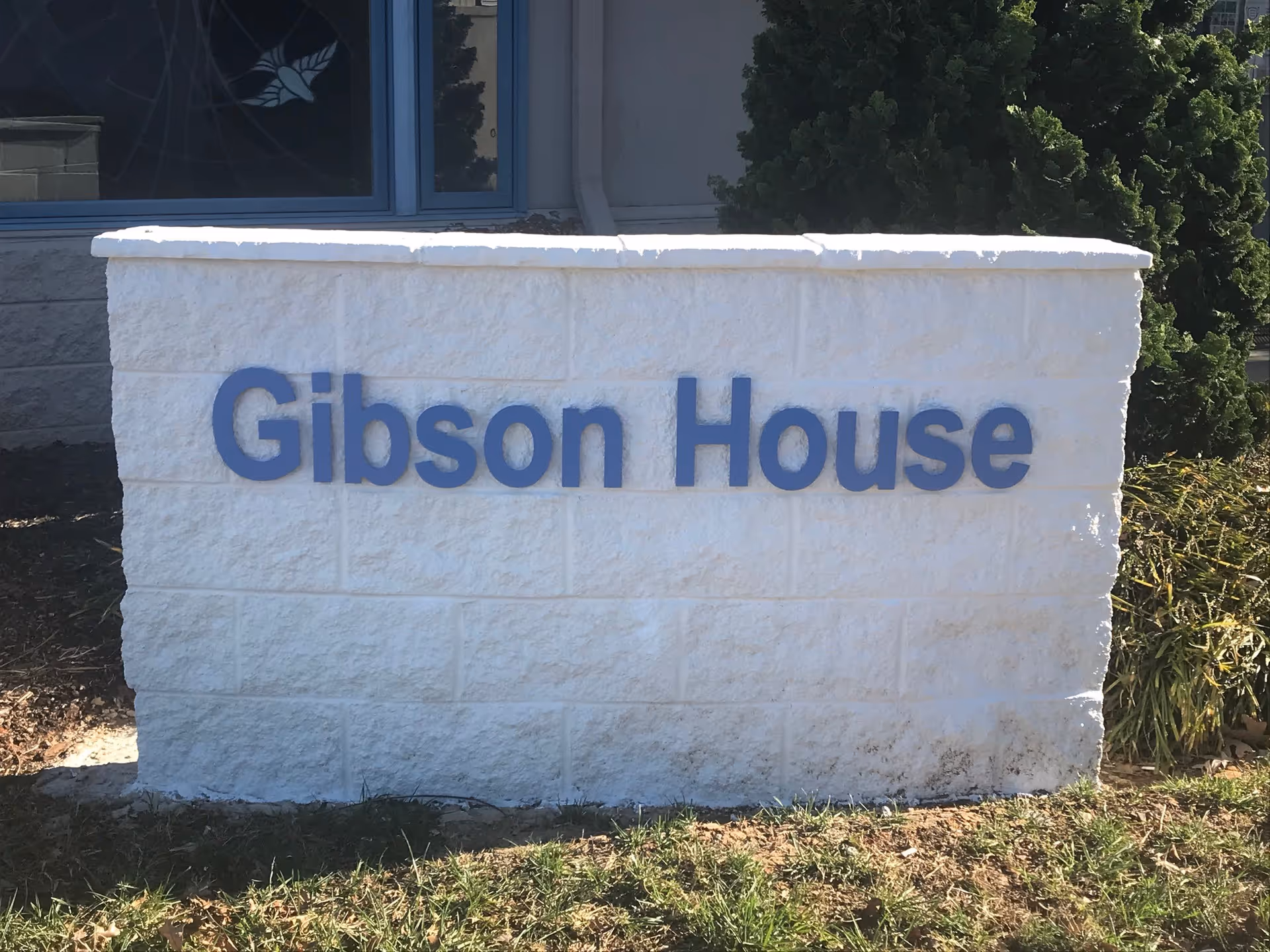 White stone sign reading Gibson House in front of a building exterior