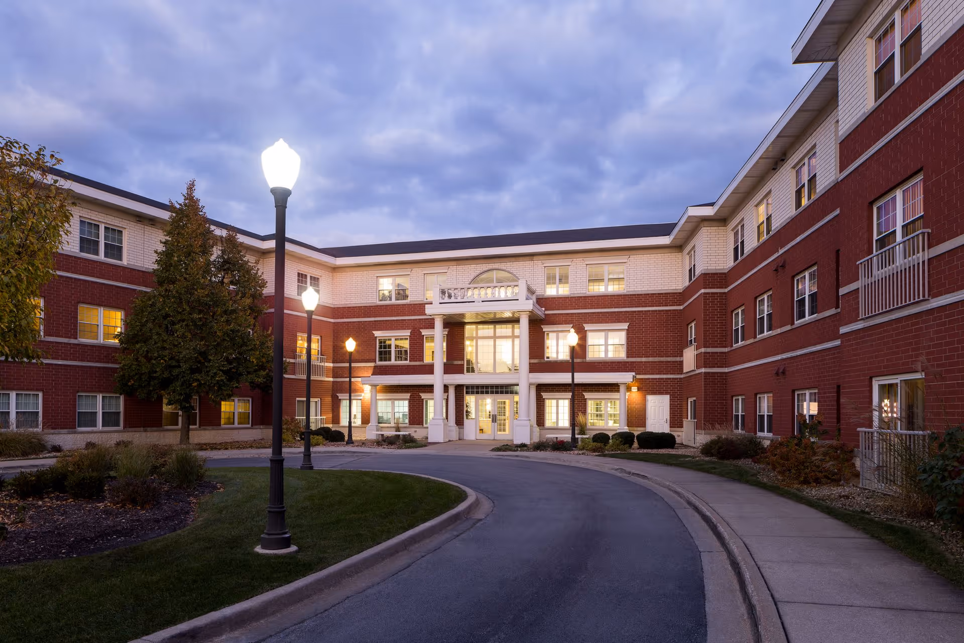 Exterior view of Hanover Place building with a curved driveway and lit entrance at dusk.
