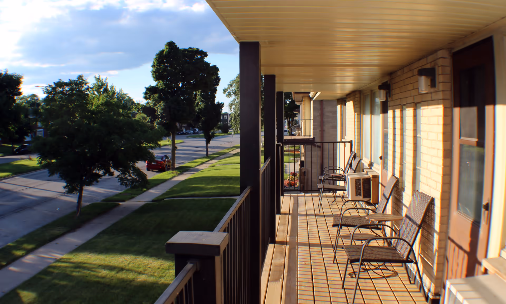 Outdoor balcony of a senior living building with multiple chairs and brick walls.