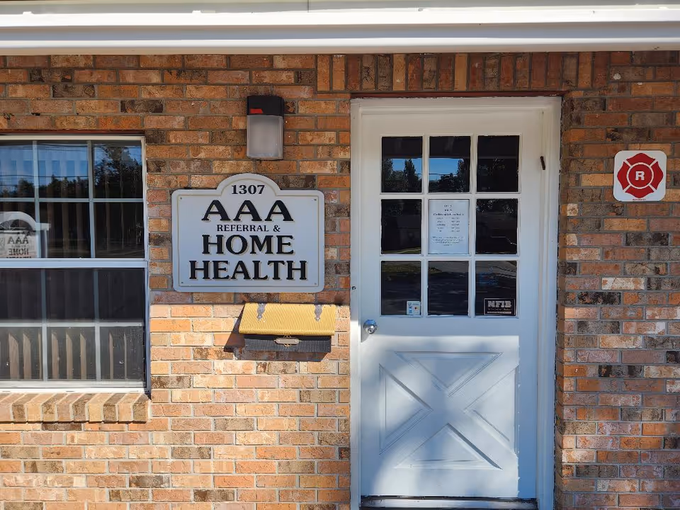 Brick building entrance with a sign reading AAA Referral and Home Health beside a window.