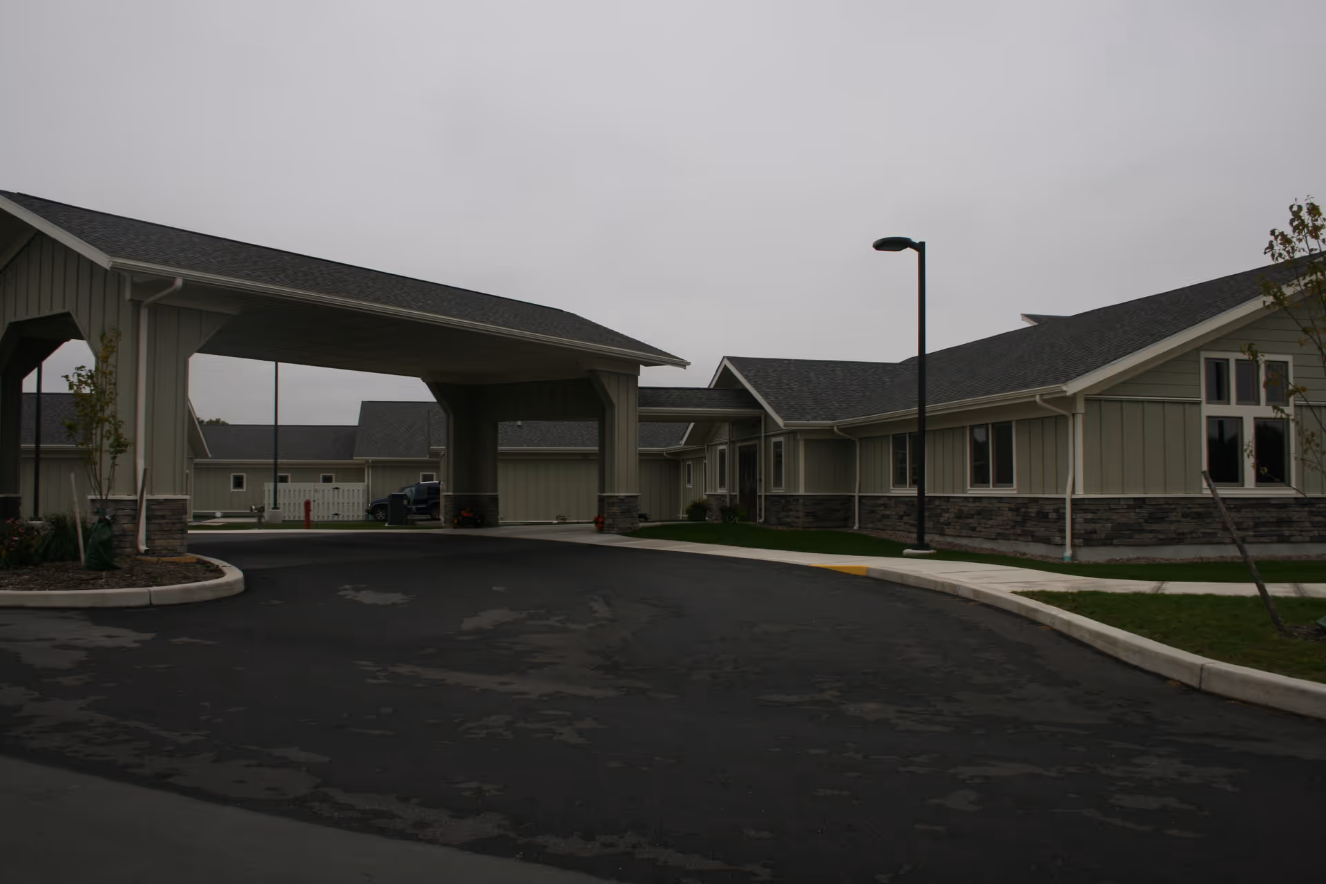 Exterior view of a senior living facility with beige buildings and a covered driveway.