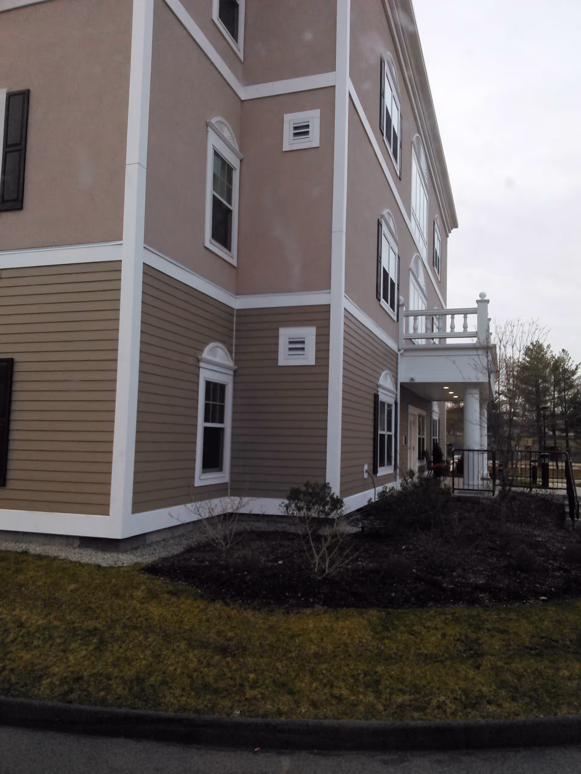 Exterior view of a multi-story beige senior living building with white trim.