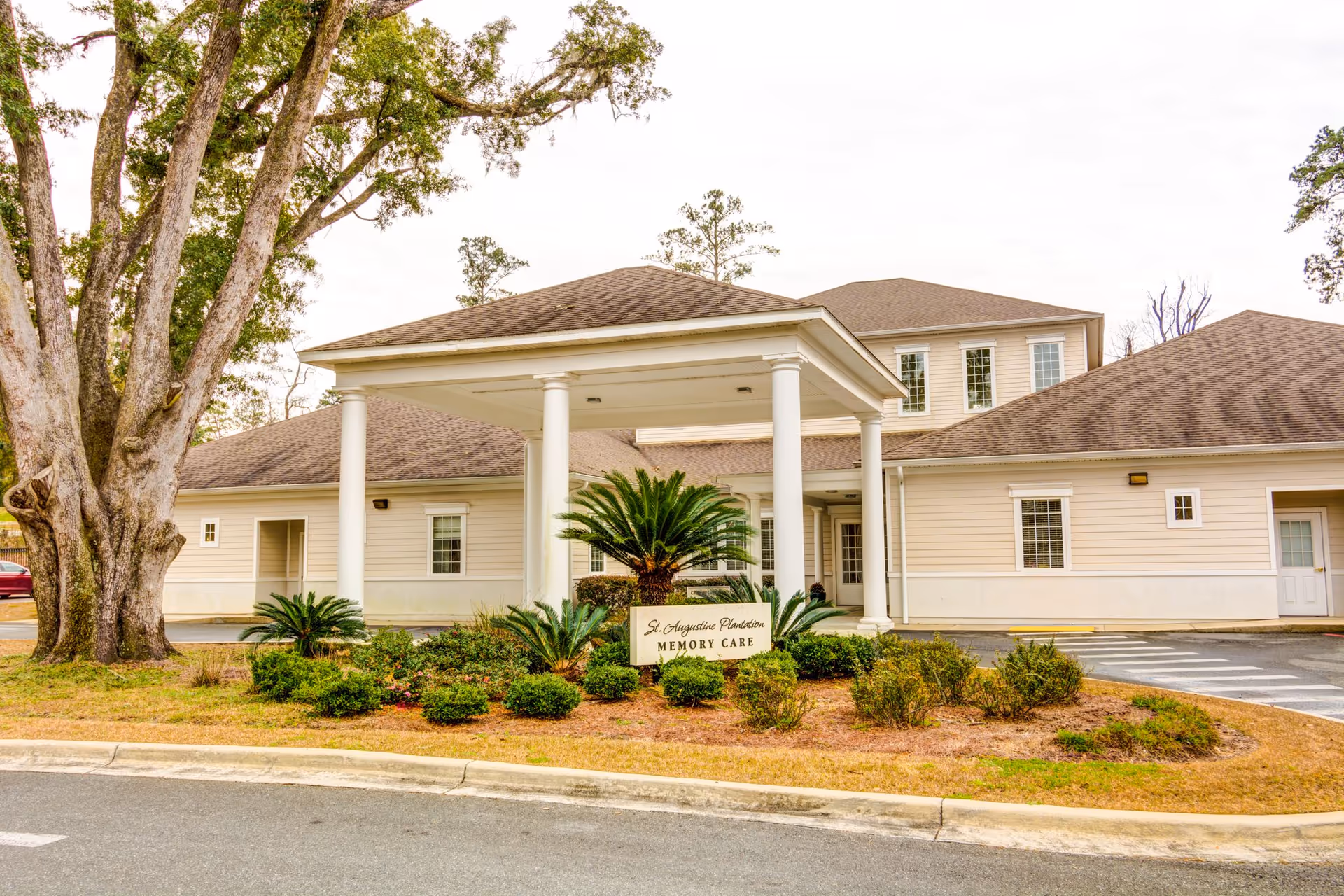 Exterior view of a beige senior living facility with a covered entrance and sign
