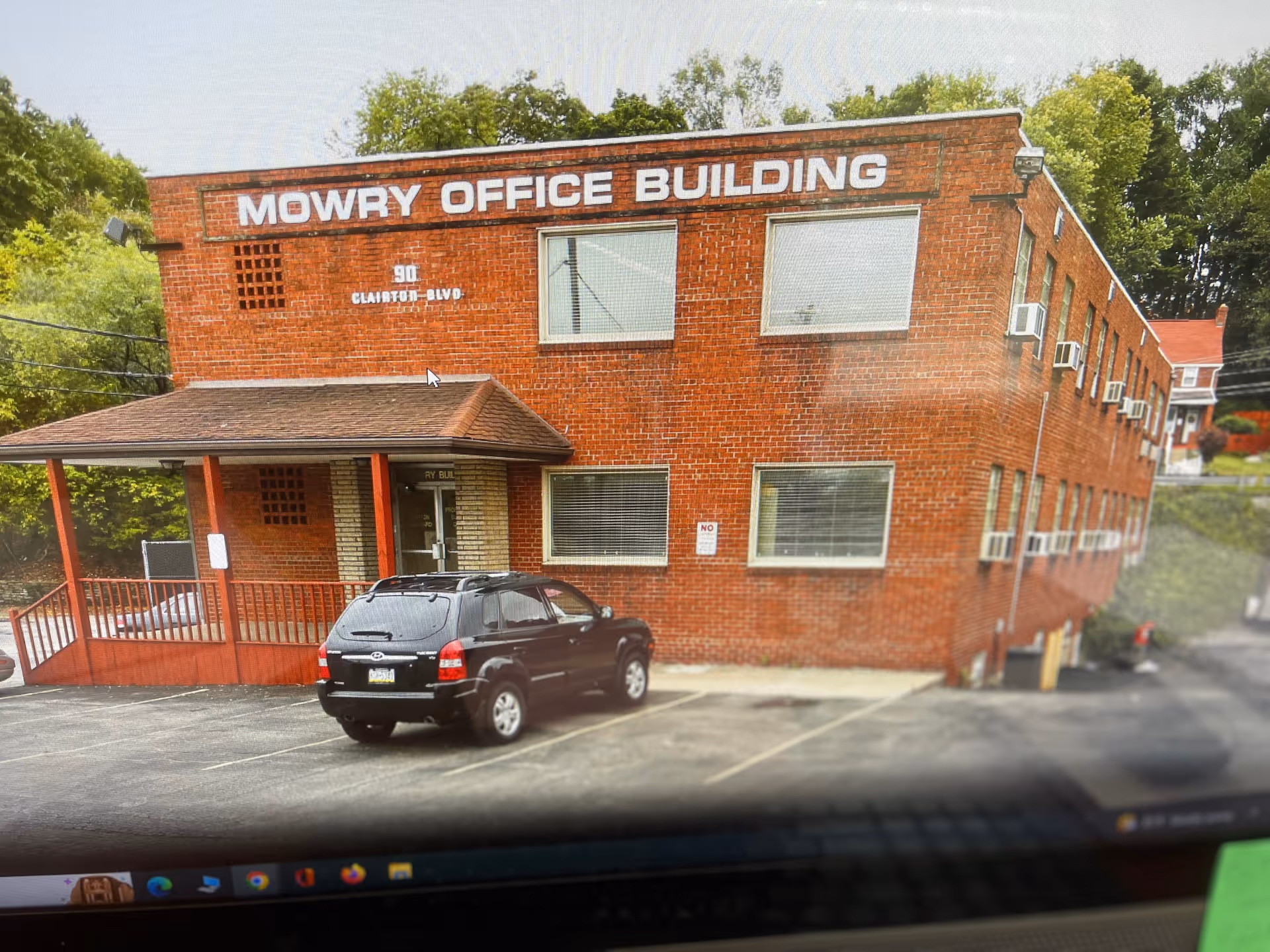 Red brick building labeled MOWRY OFFICE BUILDING with a parked black SUV.