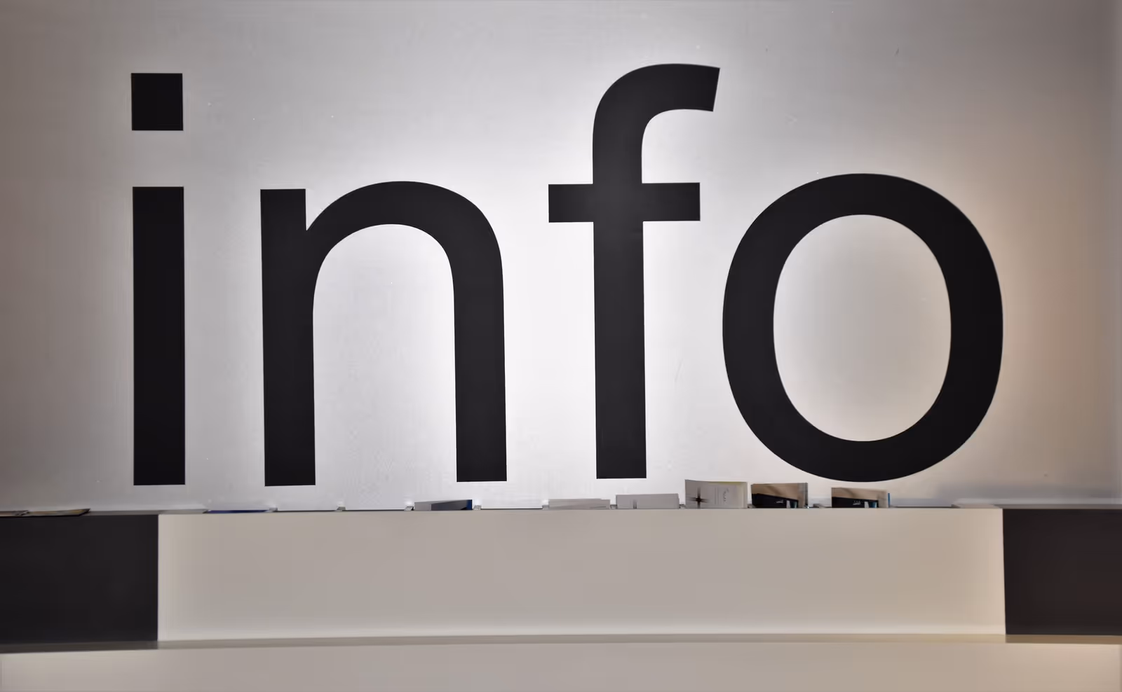 Large wall sign reading info above a reception counter in an interior space.