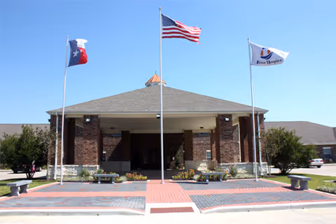 Front exterior of Harbor Hospice of Beaumont, brick building with flags and a covered entrance.