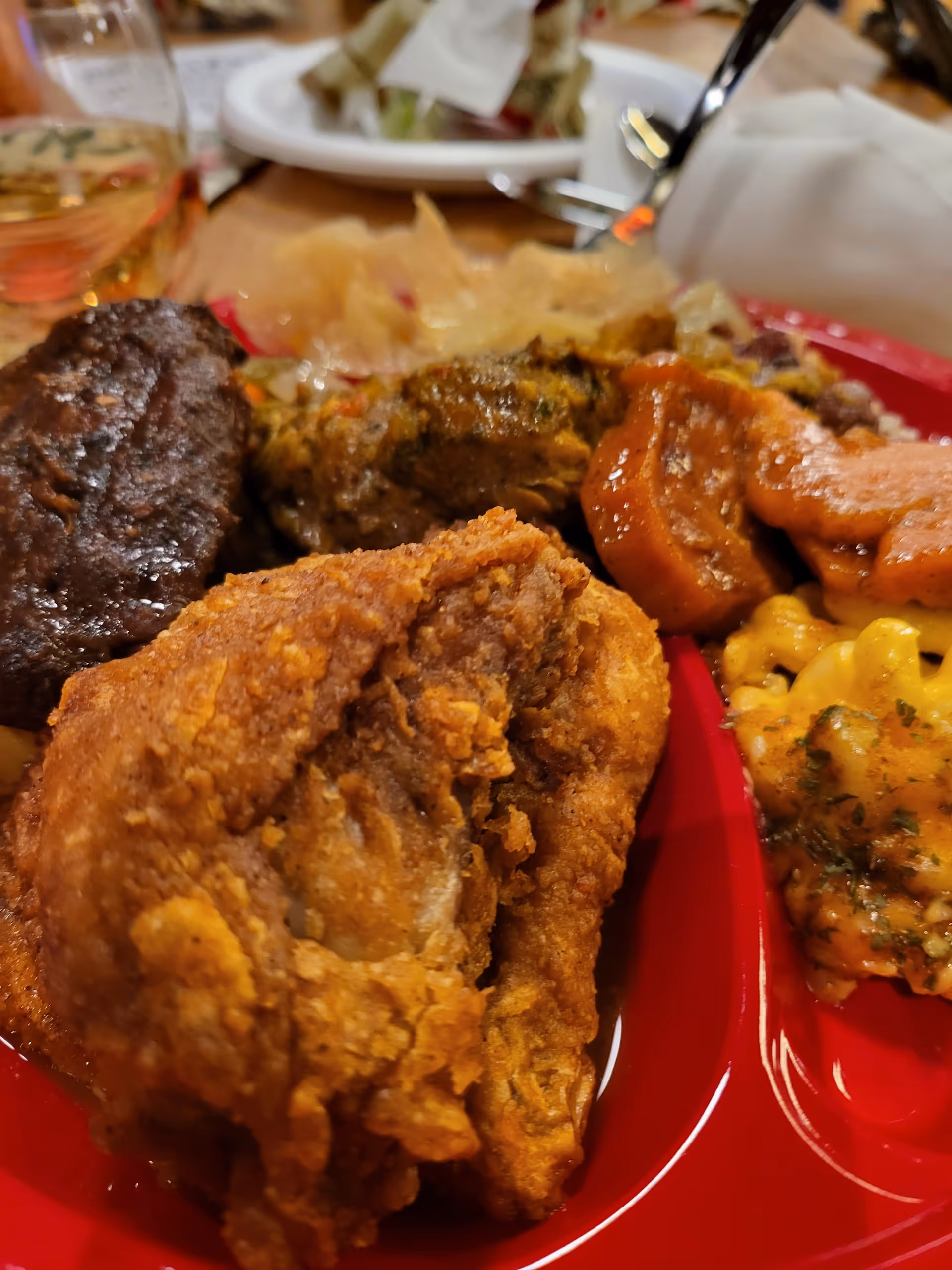 Close-up of fried chicken and sides on a red plate at a dining table.