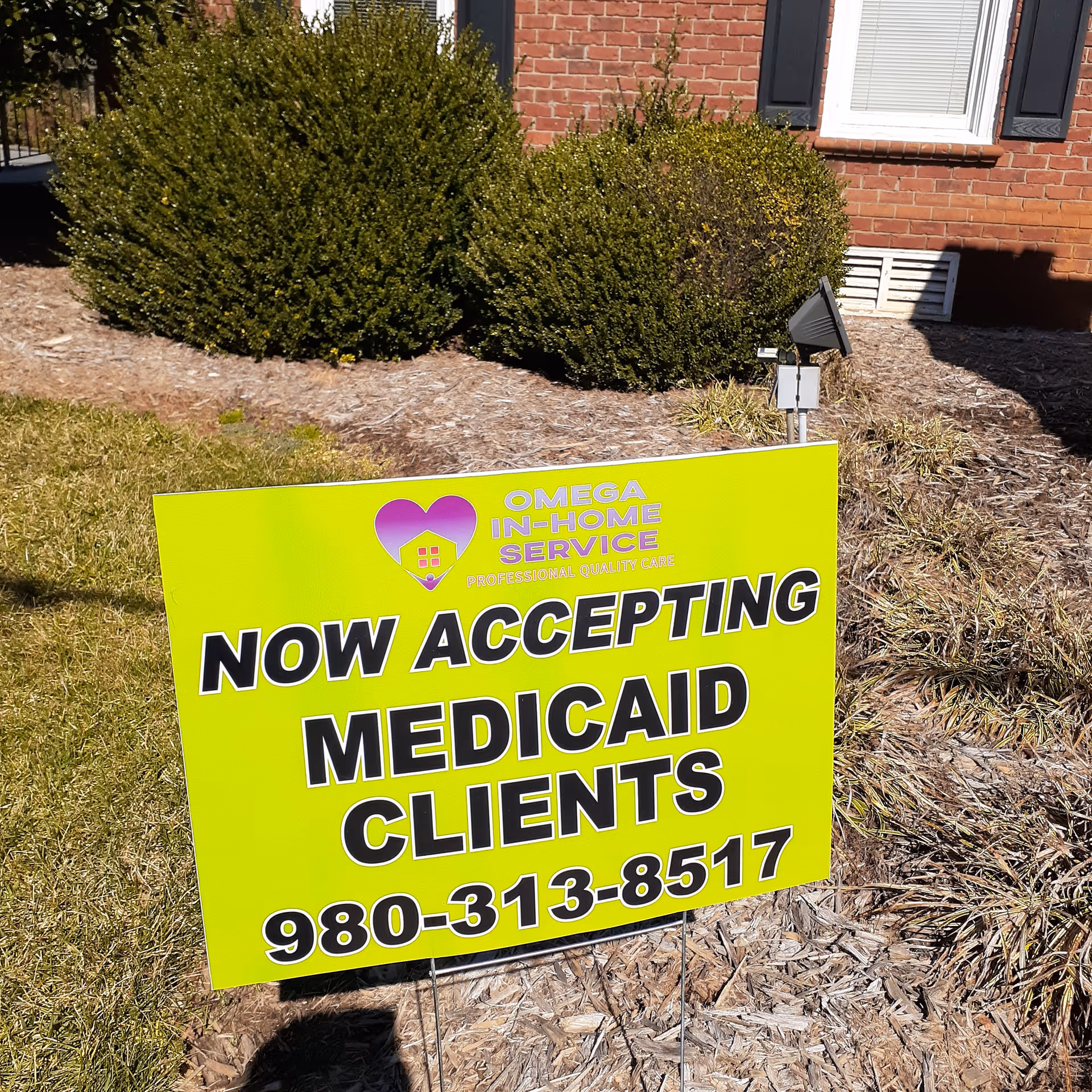 Neon lime-green sign advertising Medicaid clients outside a brick building.
