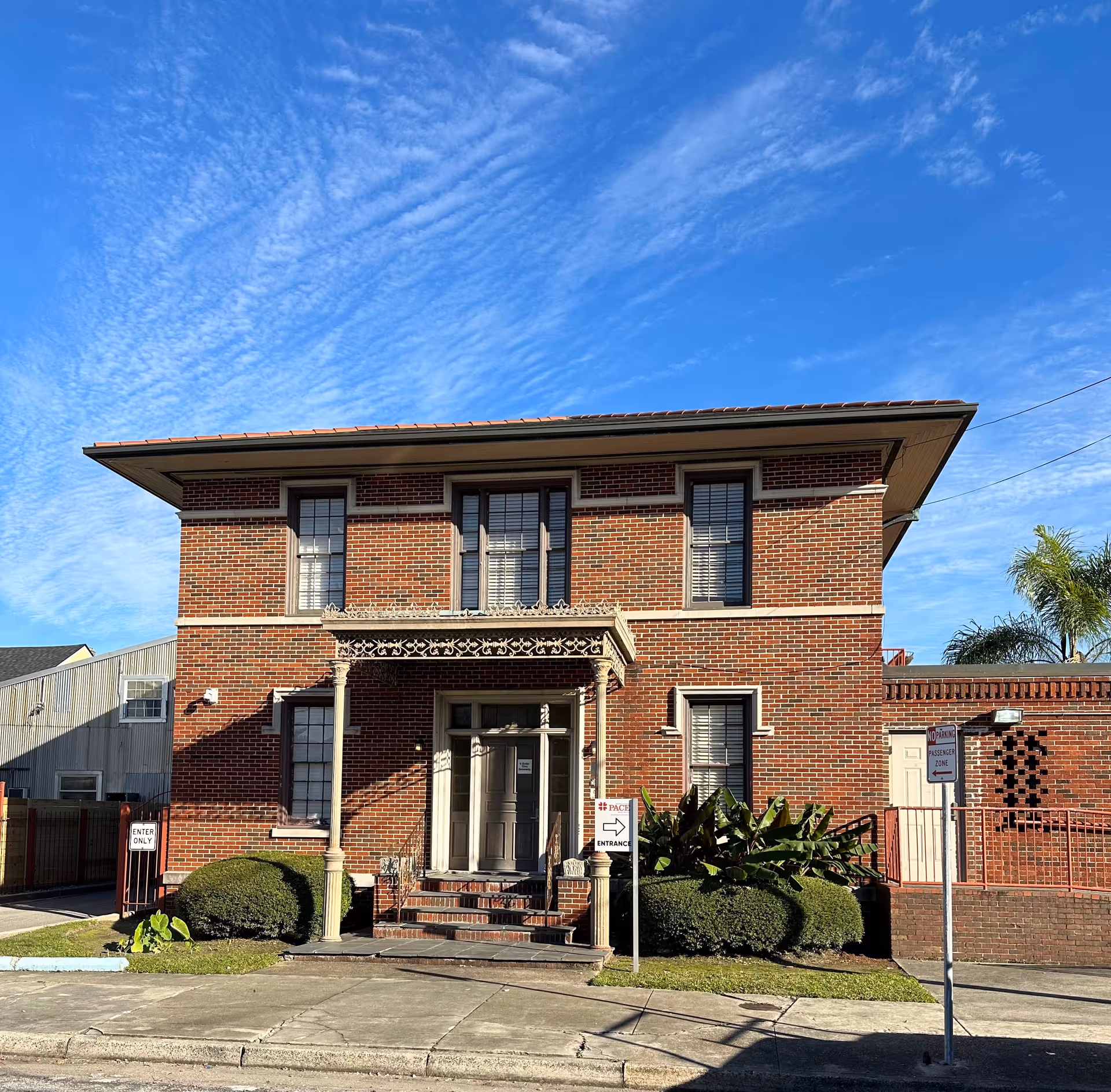 Two-story brick facility with decorative entrance under a bright blue sky.