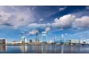 Jacksonville waterfront skyline with tall buildings reflecting on calm water.
