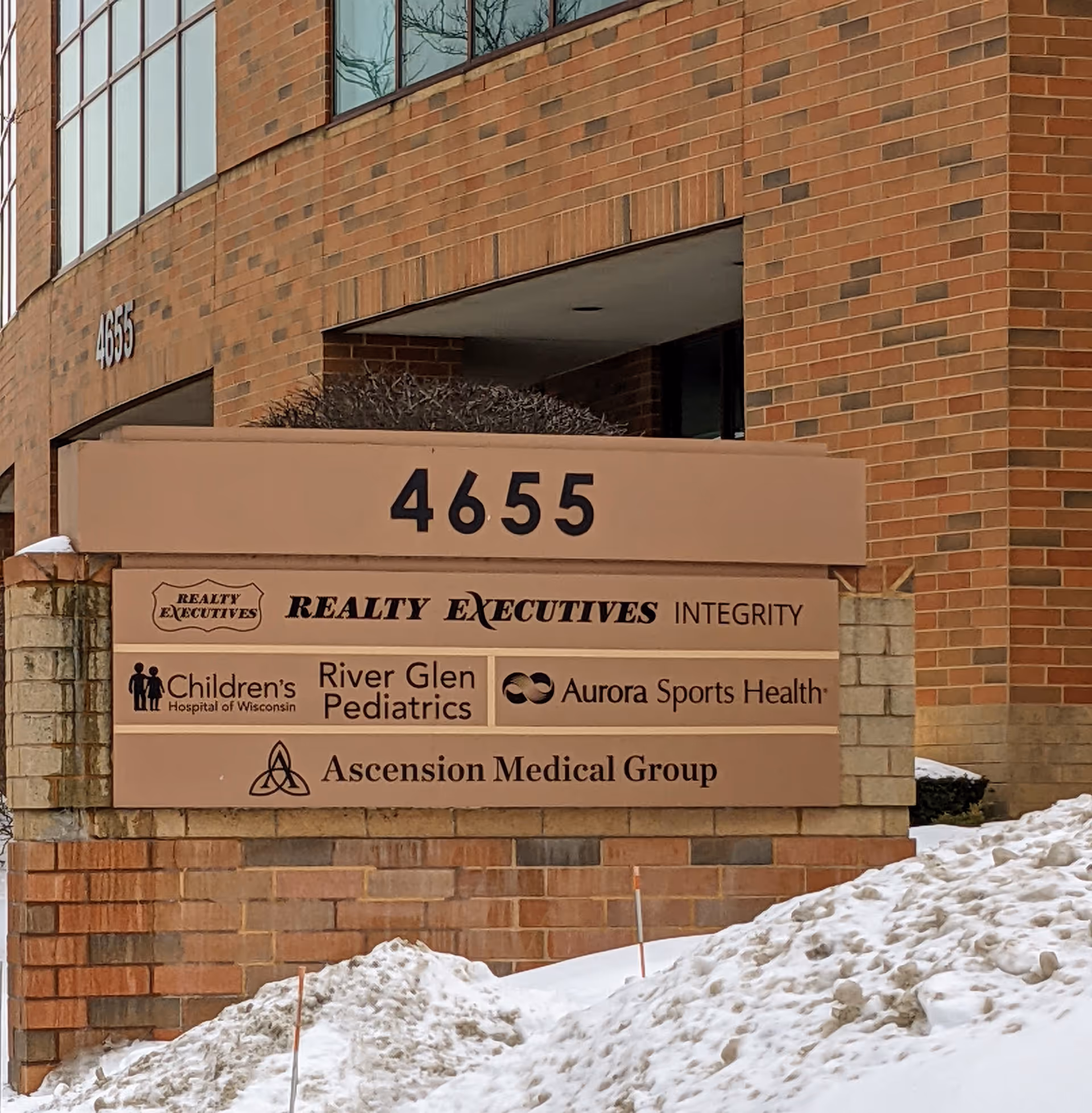 Brick building exterior with a sign listing multiple medical tenants and number 4655