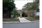 Entrance to Fair Acres Geriatric Center, brick building with walkway, sign, and bench.