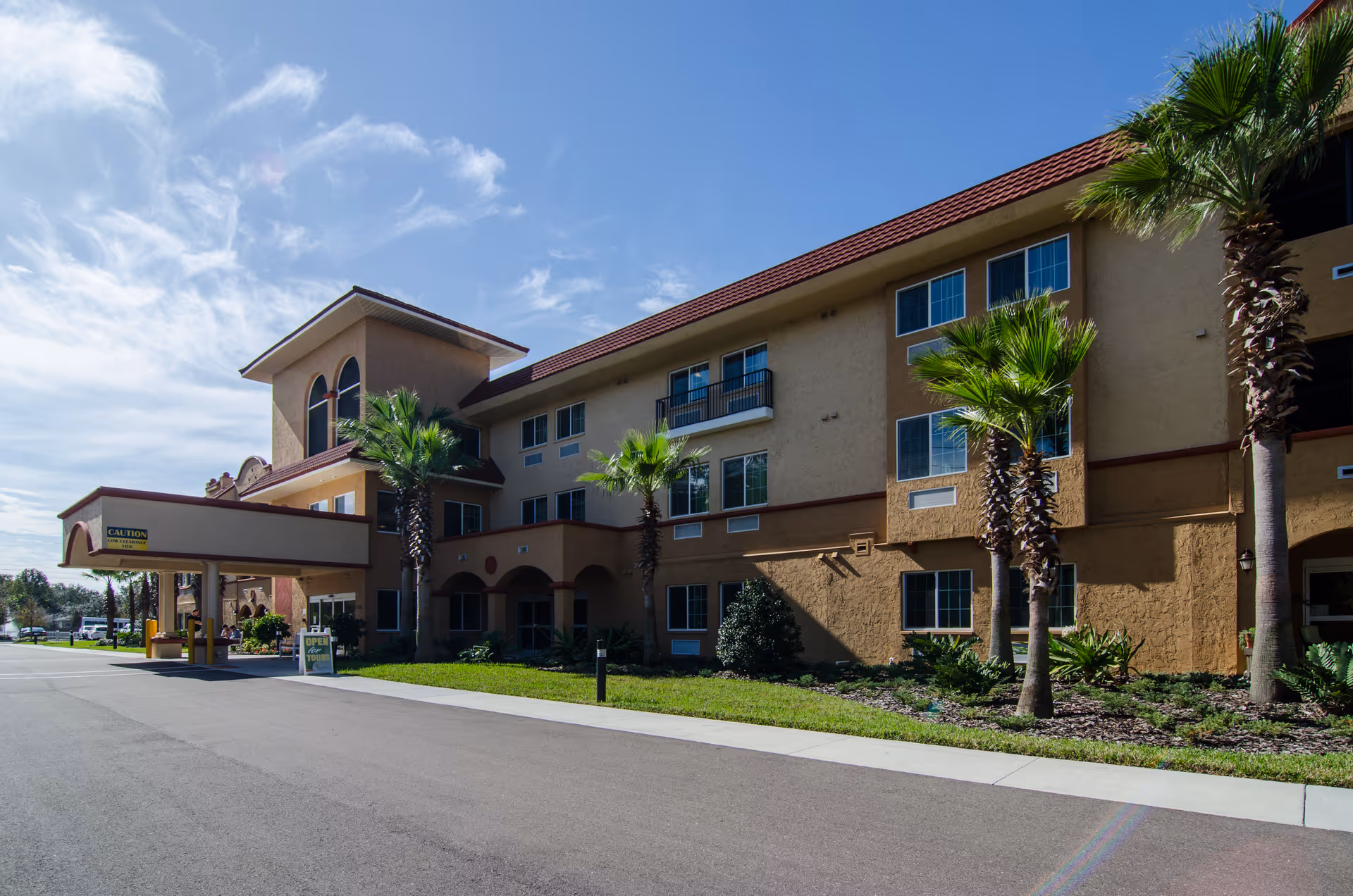 Exterior view of Seasons Largo senior living facility with palm trees and a covered entrance.