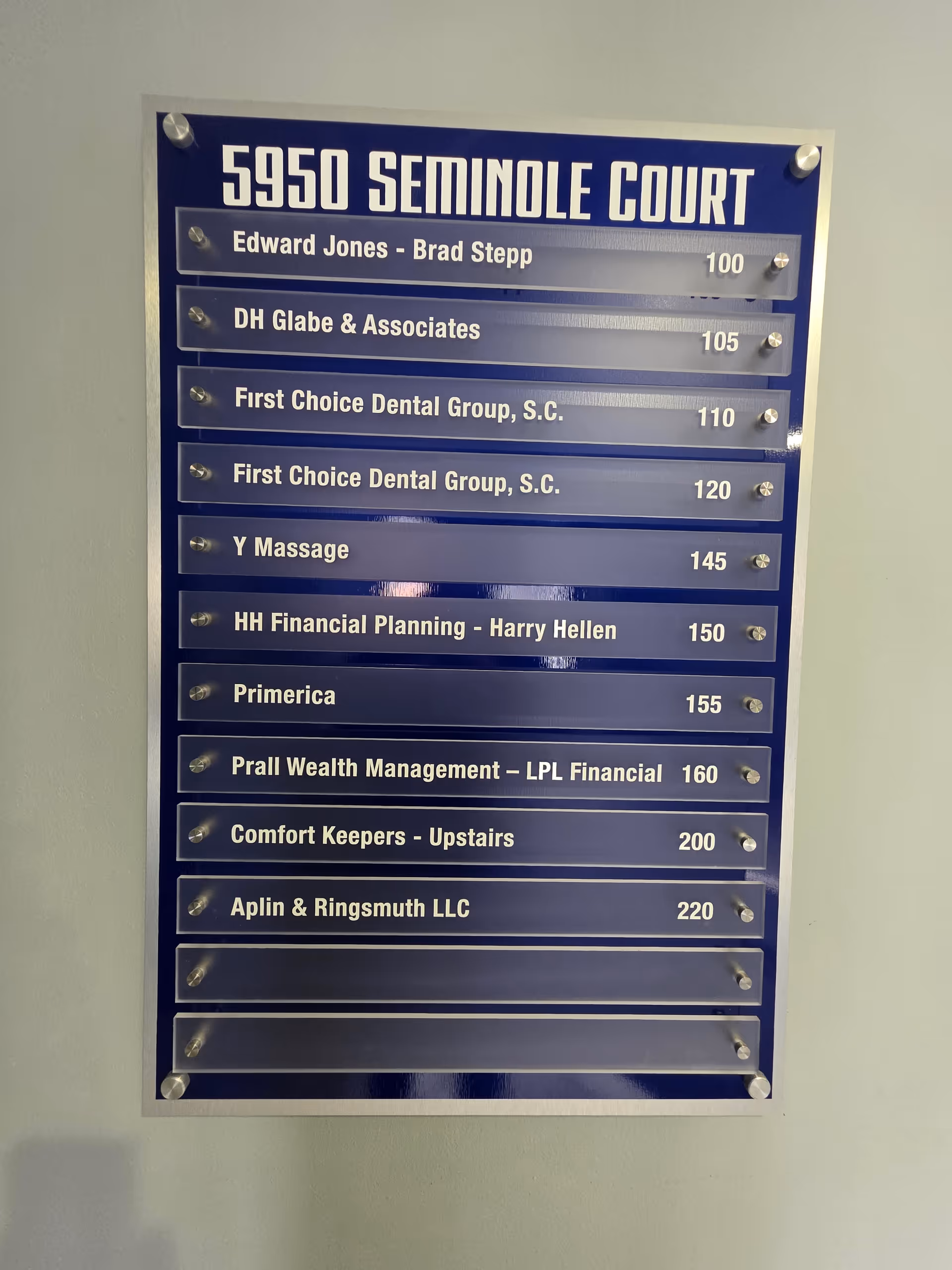 Blue directory plaque listing tenants and suite numbers mounted on a wall.