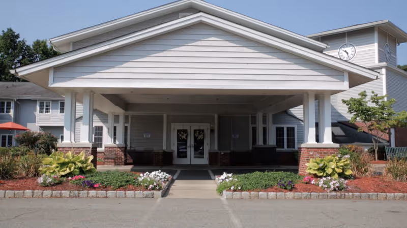 Front view of CareOne at Wayne Assisted Living entrance with landscaping and clock tower.
