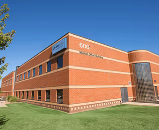 Brick medical building marked 600 with curved glass entrance and green lawn.