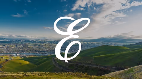 Wide landscape of rolling green hills with a large white cursive E logo in foreground.