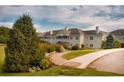 RiverMead senior living exterior with curved driveway, manicured lawn, and residential-style buildings.