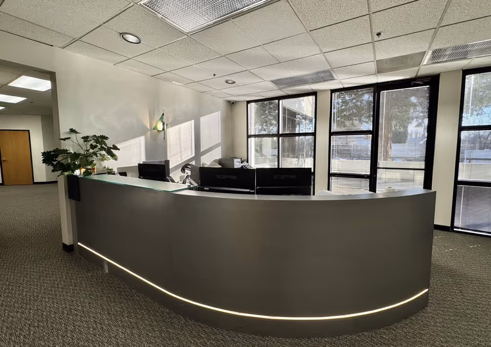 Modern curved reception desk in a spacious, sunlit lobby with large windows.