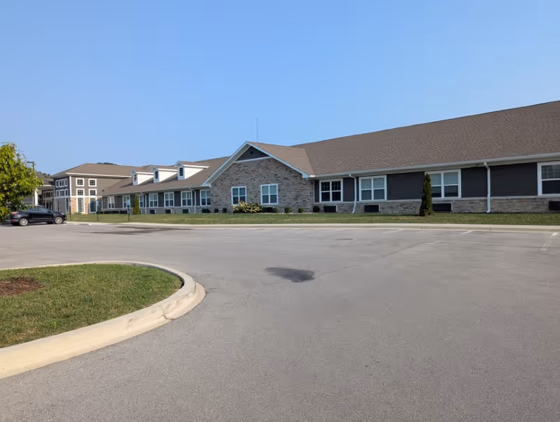 Exterior view of Rivercrest Senior Living building with brick facade and parking lot.