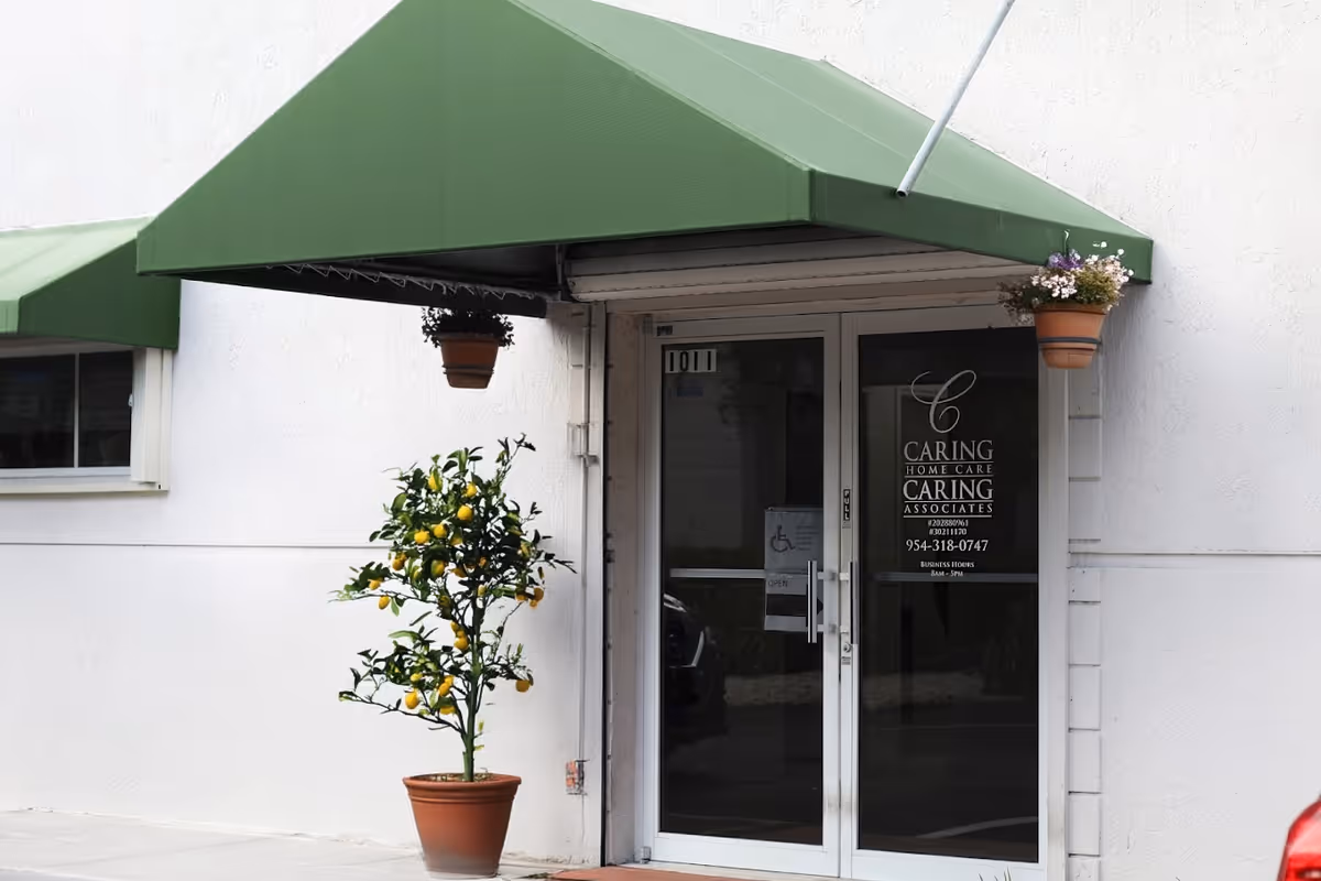 Exterior view of Caring Home Care entrance with green awning and potted lemon tree.