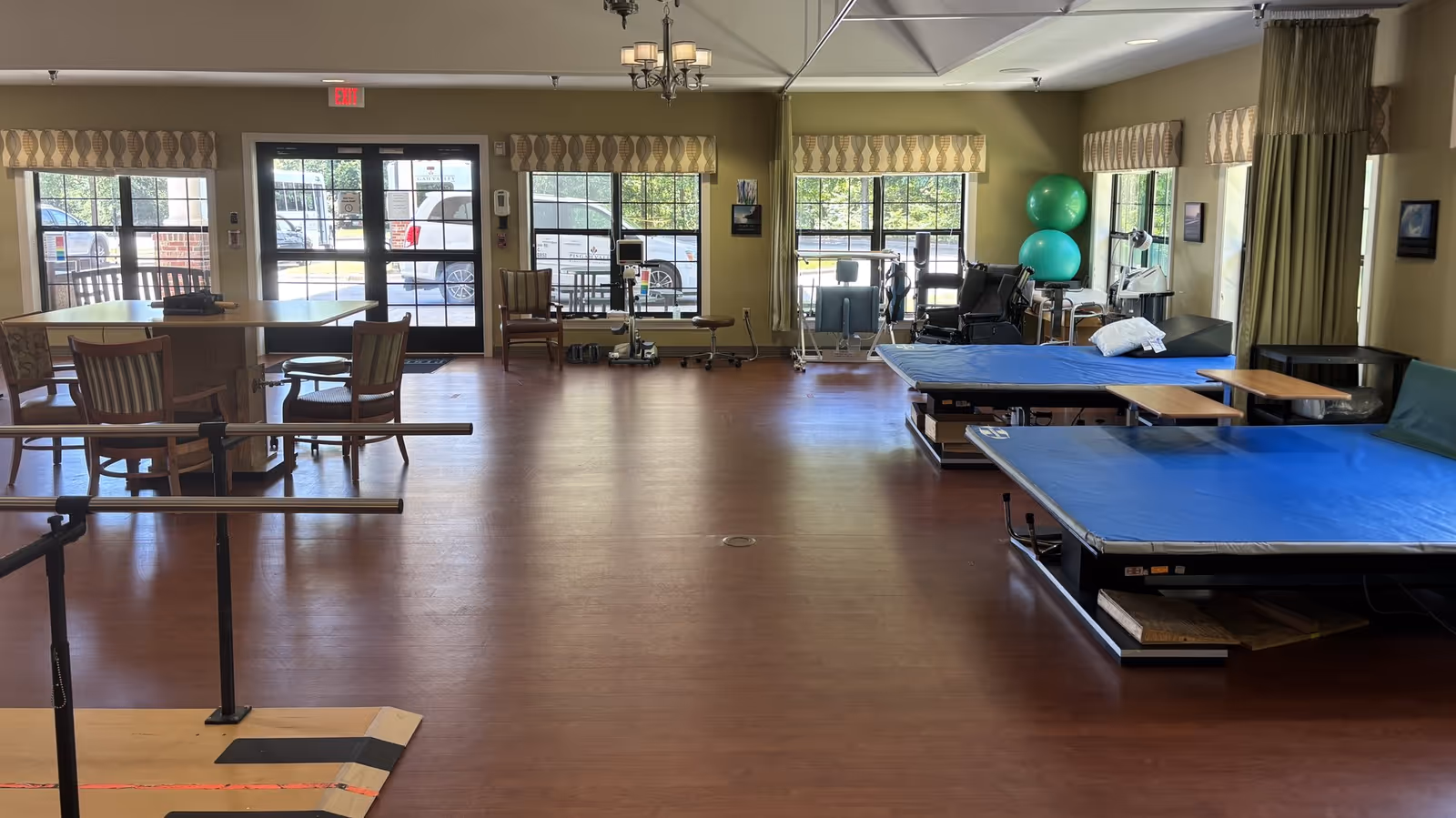 Spacious rehabilitation gym at Pisgah Manor with mats, parallel bars, and fitness equipment.