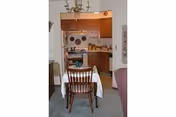 Dining room with a table, chairs, and an open kitchen visible in the background.