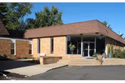 Front view of a brick senior living facility entrance with glass doors.