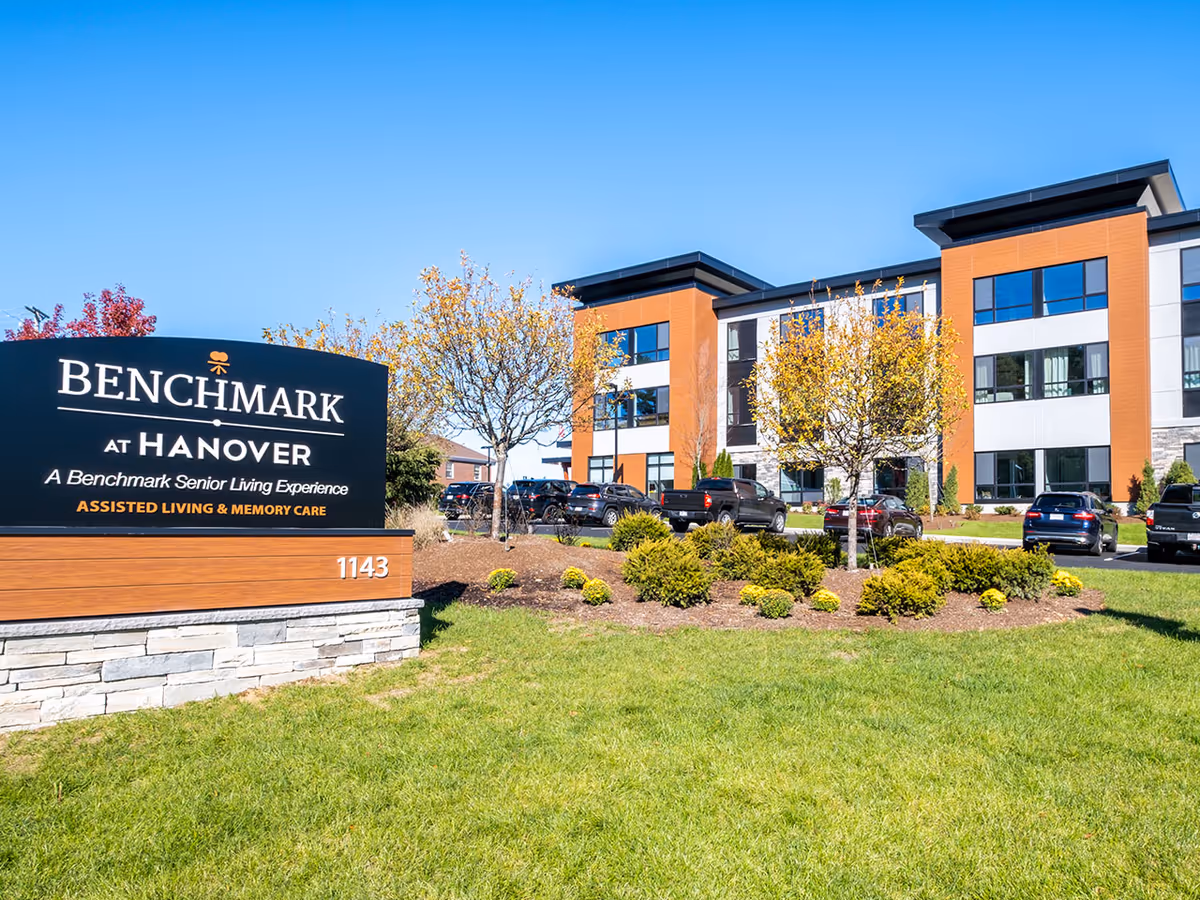 Exterior view of Benchmark at Hanover senior living facility with sign and landscaped grounds.