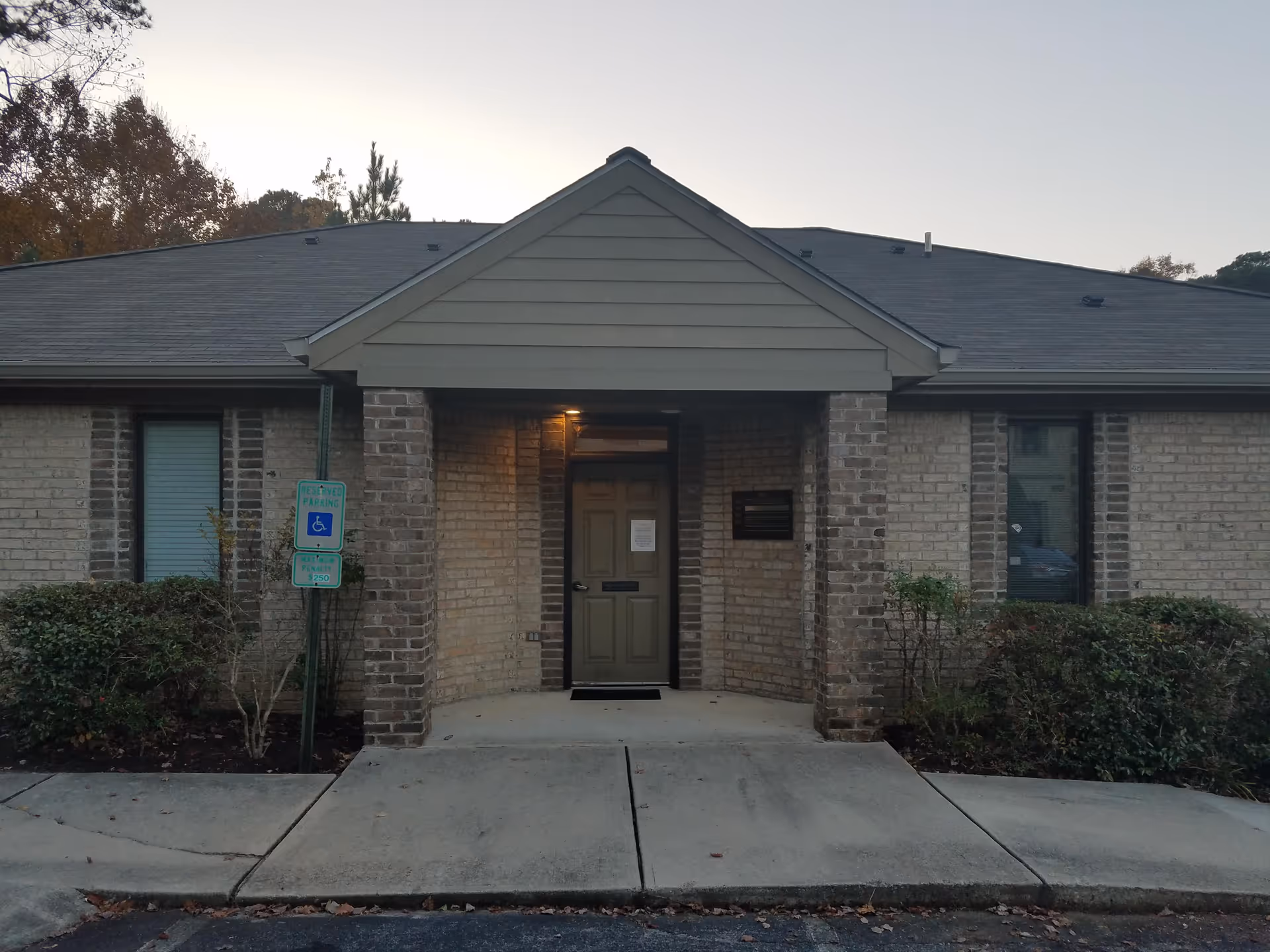 Brick exterior of a facility entrance with a covered doorway and landscaping.