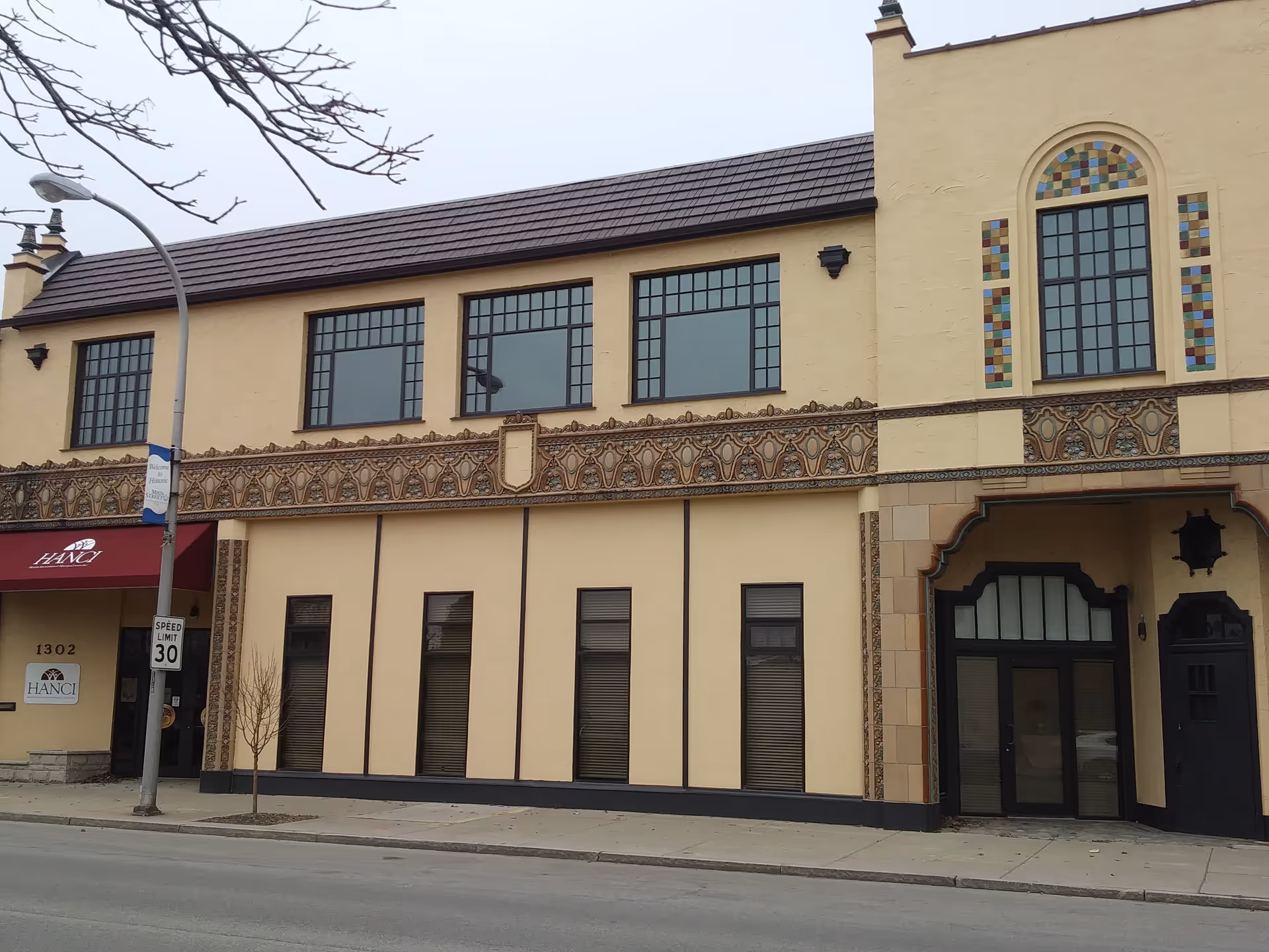 Two-story beige building facade with decorative trim and large street-facing windows.