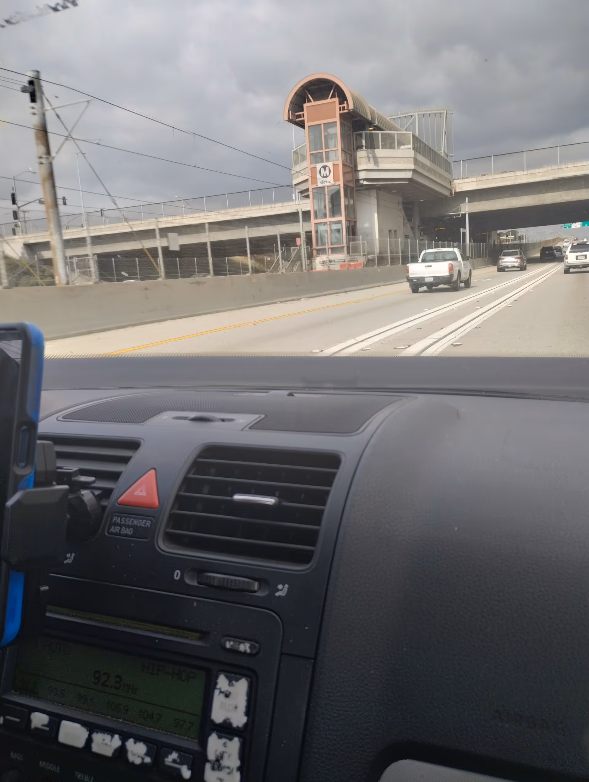 Dashboard view from a car toward a modern elevated transit station ahead.