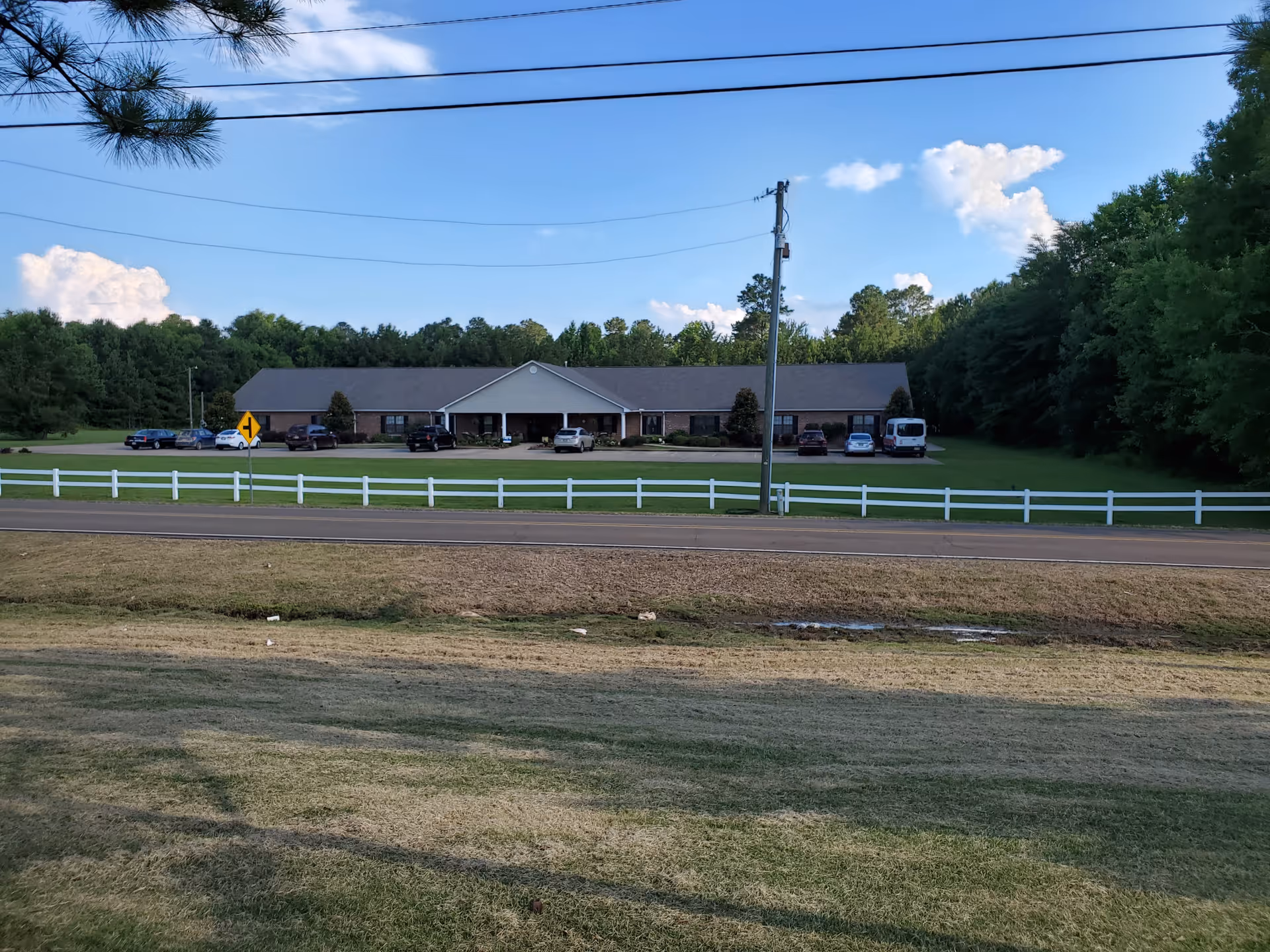 Single-story Montgomery Gardens facility with central entrance, parking, and a white fence.