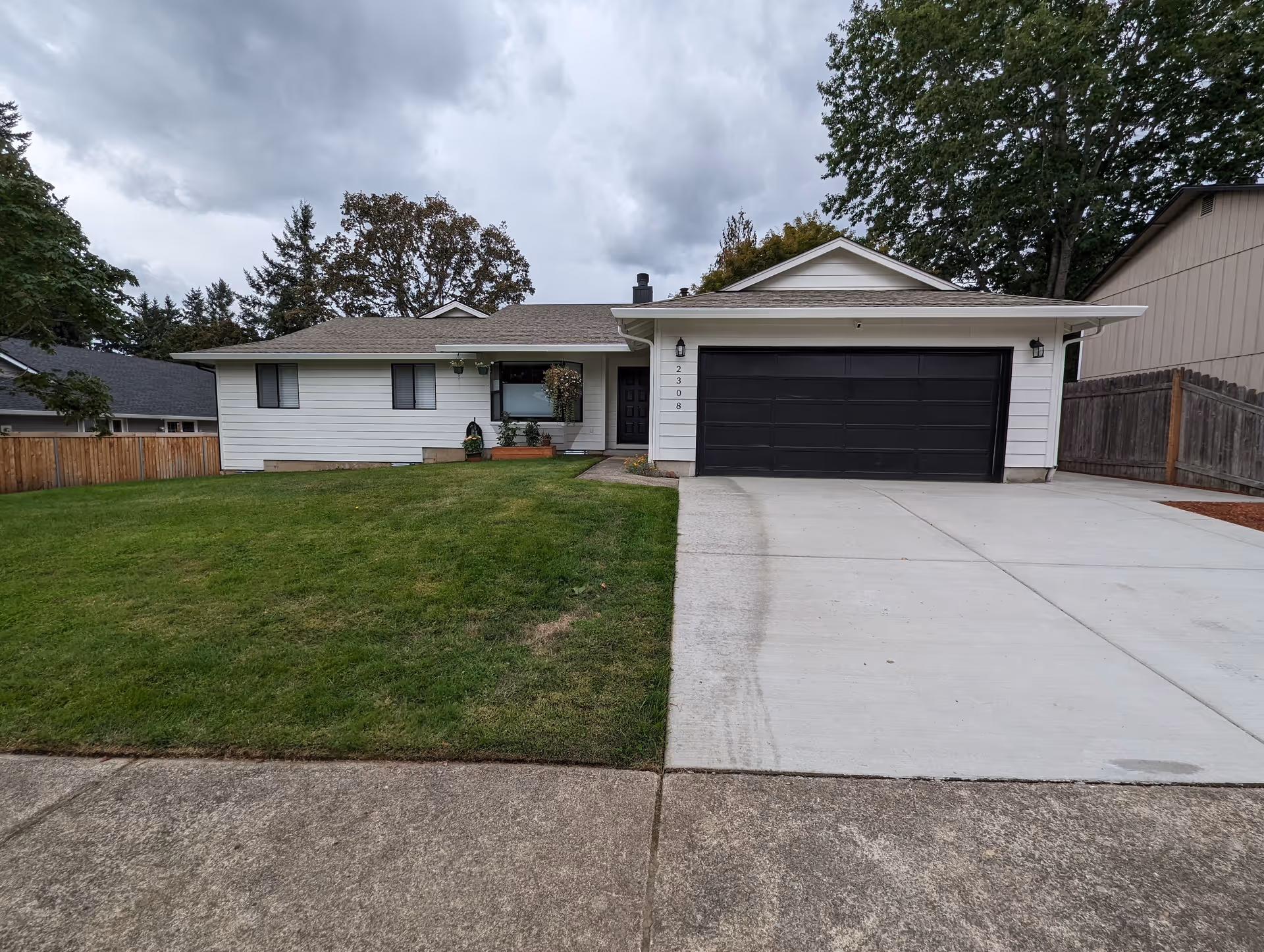 Single-story white house with a black garage door and a grassy front yard.