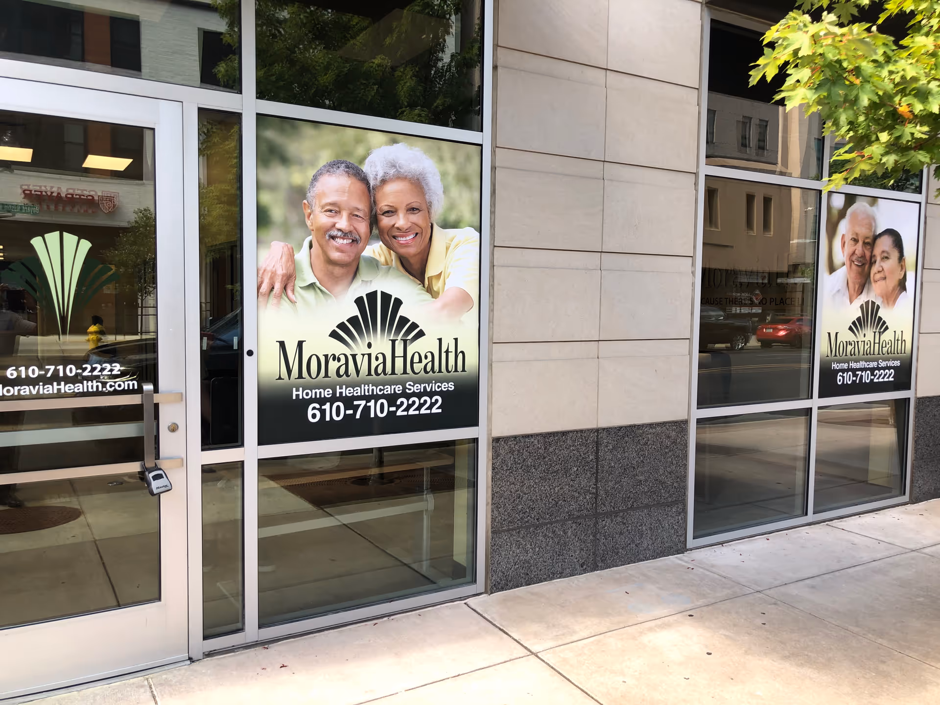 Storefront of Moravia Health with large posters of smiling seniors on glass windows.