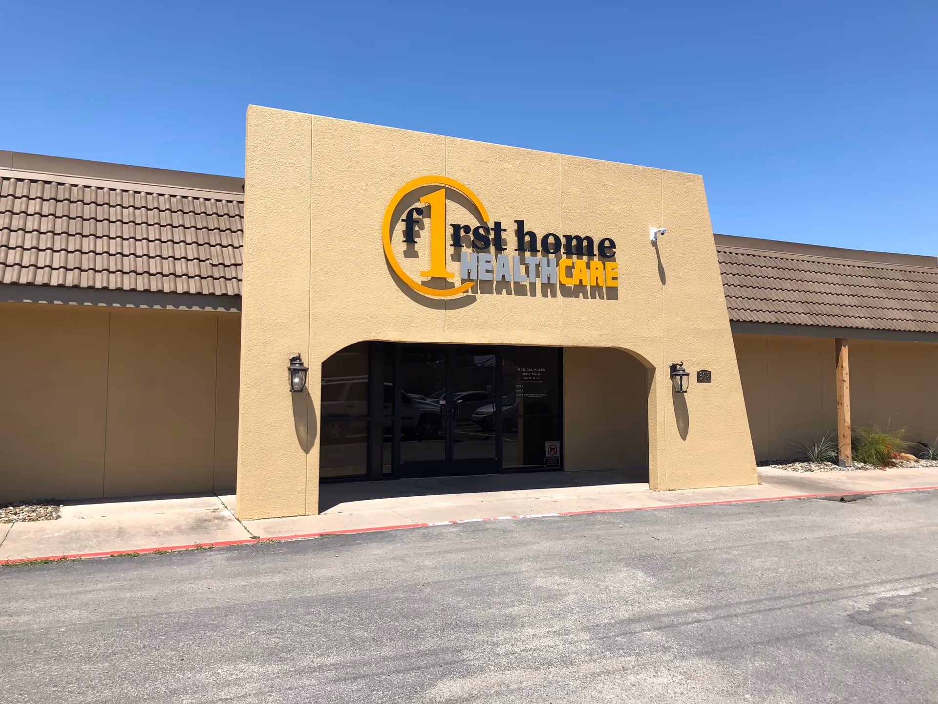 Beige building with 'First Home Healthcare' sign and glass front entrance.