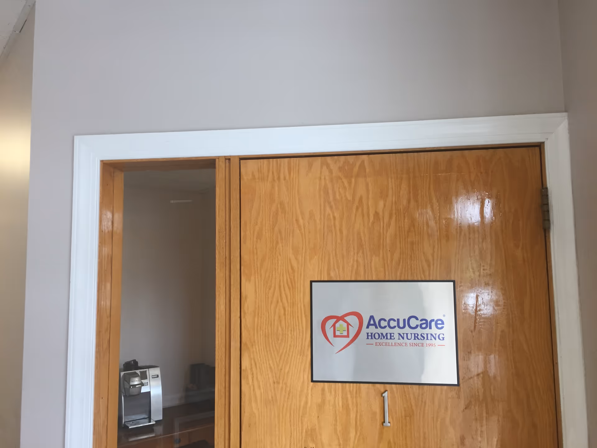 Wooden door with AccuCare Home Nursing sign; coffee machine visible in adjacent room.