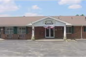 Single-story brick Miller's Merry Manor entrance with peaked canopy and patriotic bunting.