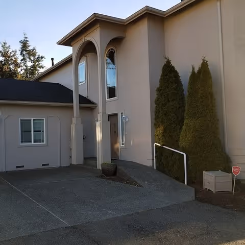 Exterior view of Mukilteo Sunrise facility showing entrance arches, ramp, and evergreen trees.