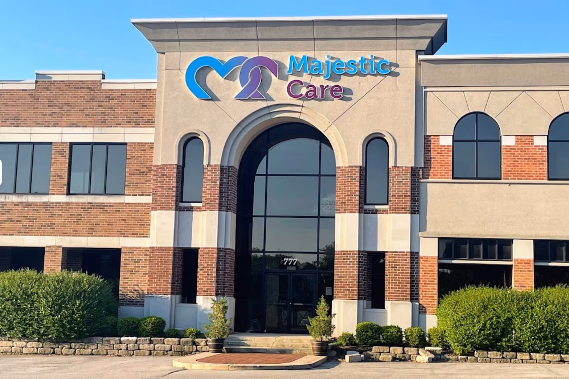 Front view of Majestic Care facility with arched entrance and brick facade.