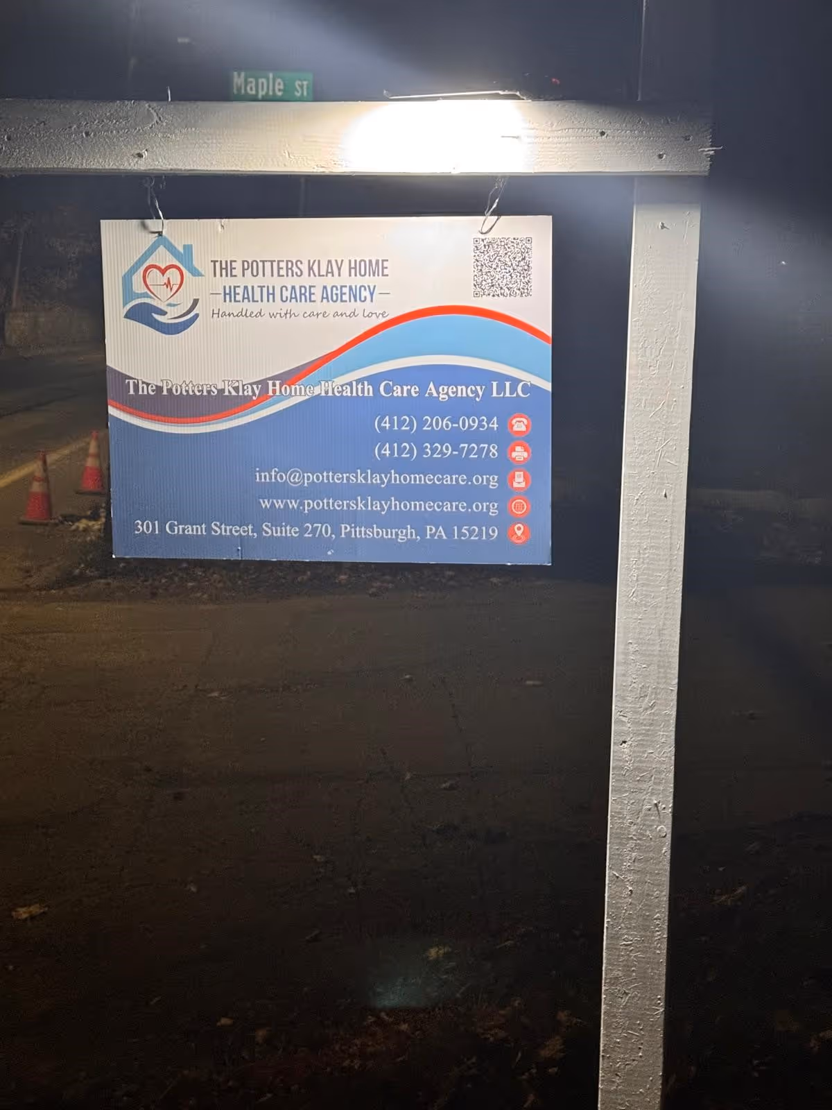 Outdoor sign for The Potters Klay Home Health Care Agency on a frame near Maple Street