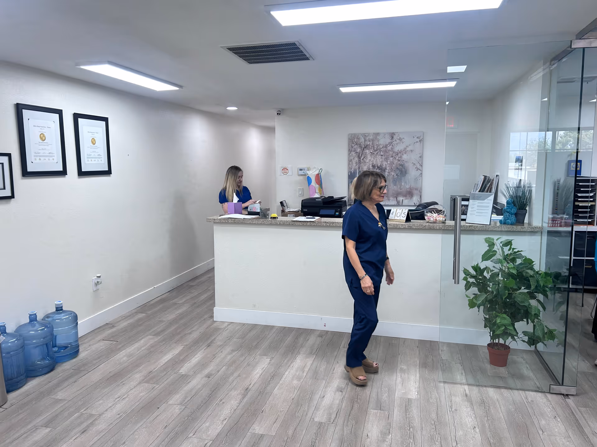 Reception desk in a modern lobby with two staff members and glass divider.