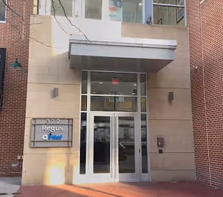Glass entrance to a brick building with a metal canopy and Regus sign