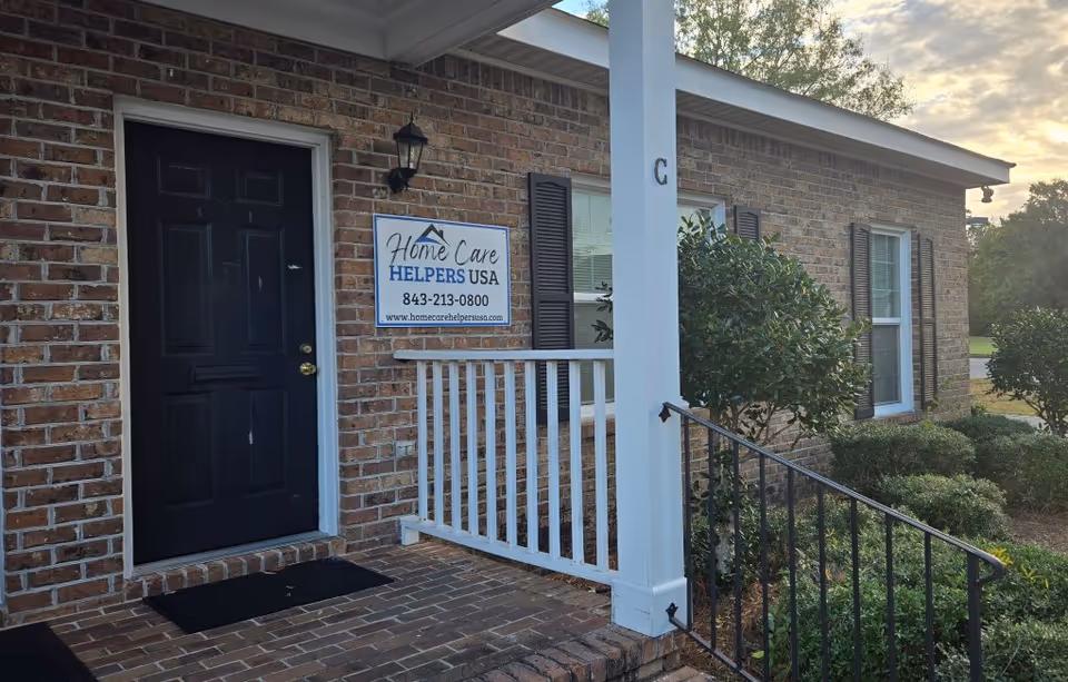 Brick building entrance with a small porch and Home Care Helpers USA sign.