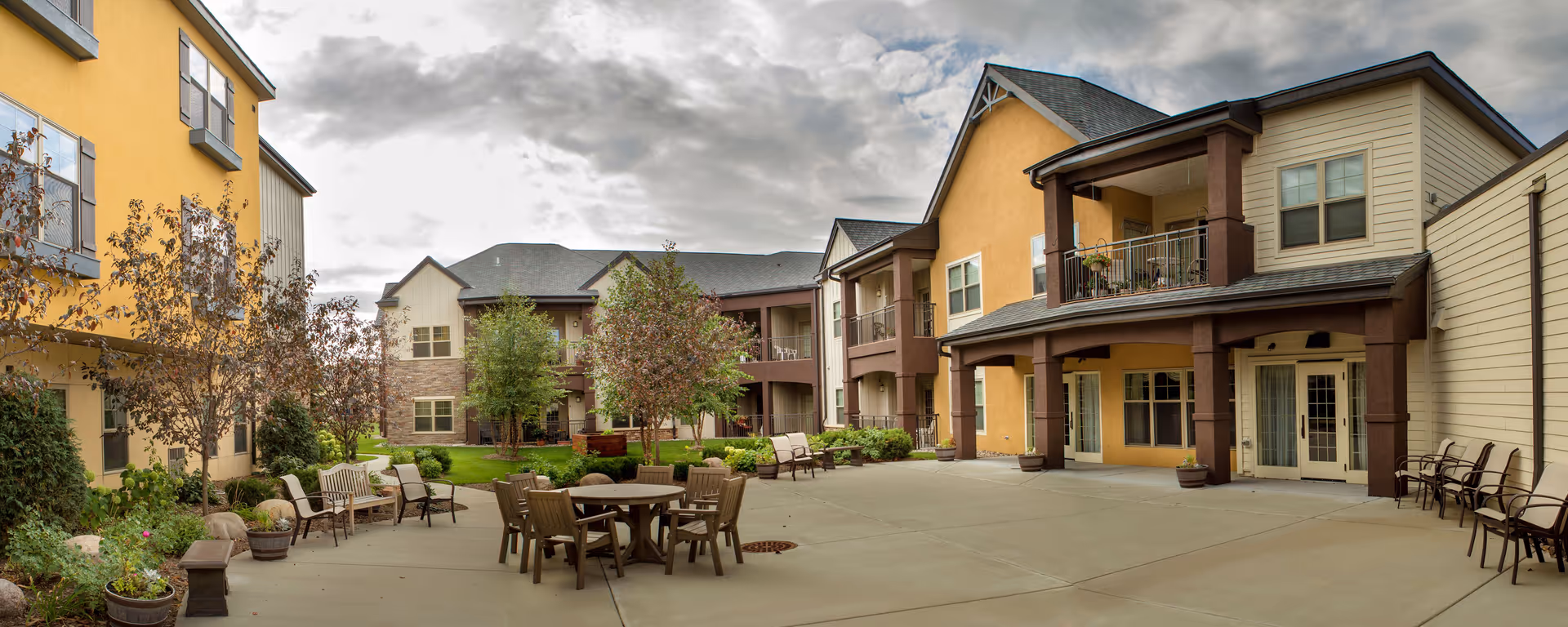 Outdoor courtyard at Kingsway Retirement Living with tables, chairs, and landscaped greenery.