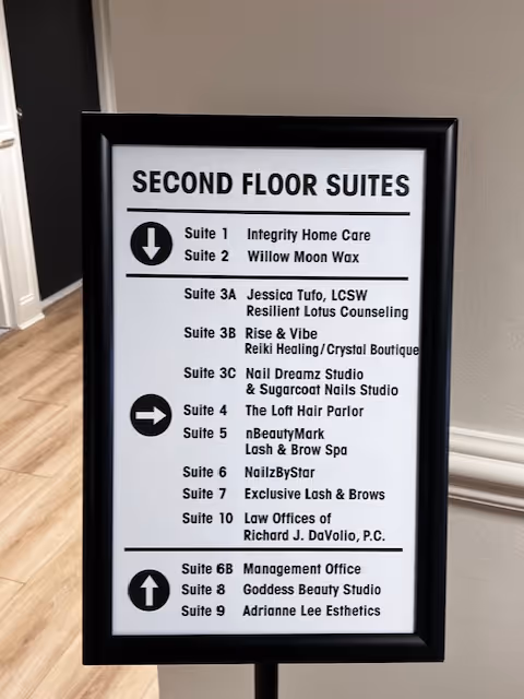Framed interior directory sign listing second-floor suites in a hallway.