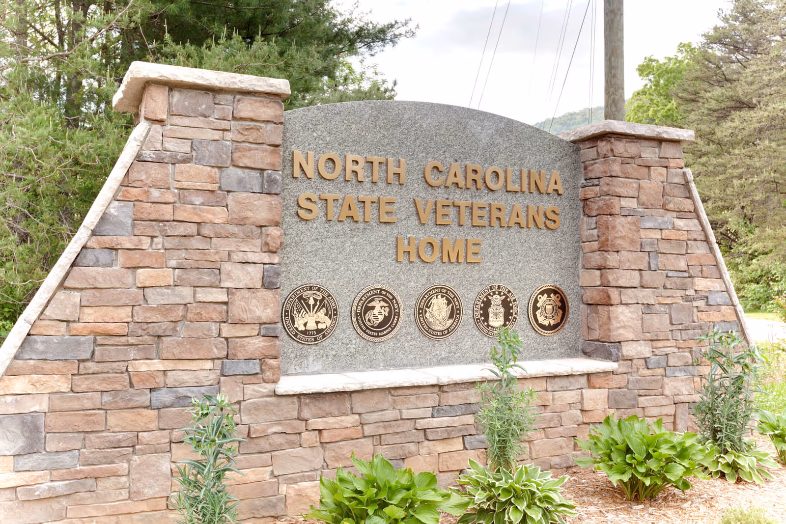 Stone entrance sign reading North Carolina State Veterans Home with decorative medallions