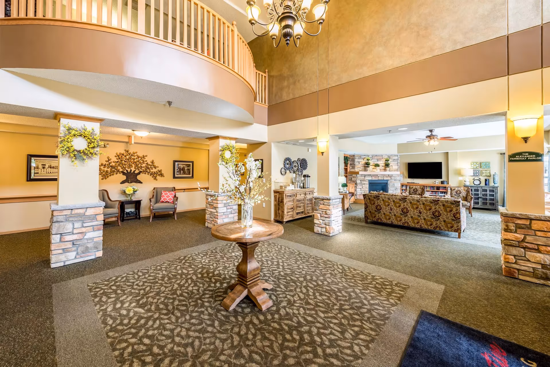 Interior senior living common area with couches, a round centerpiece table, and decorative stone pillars.