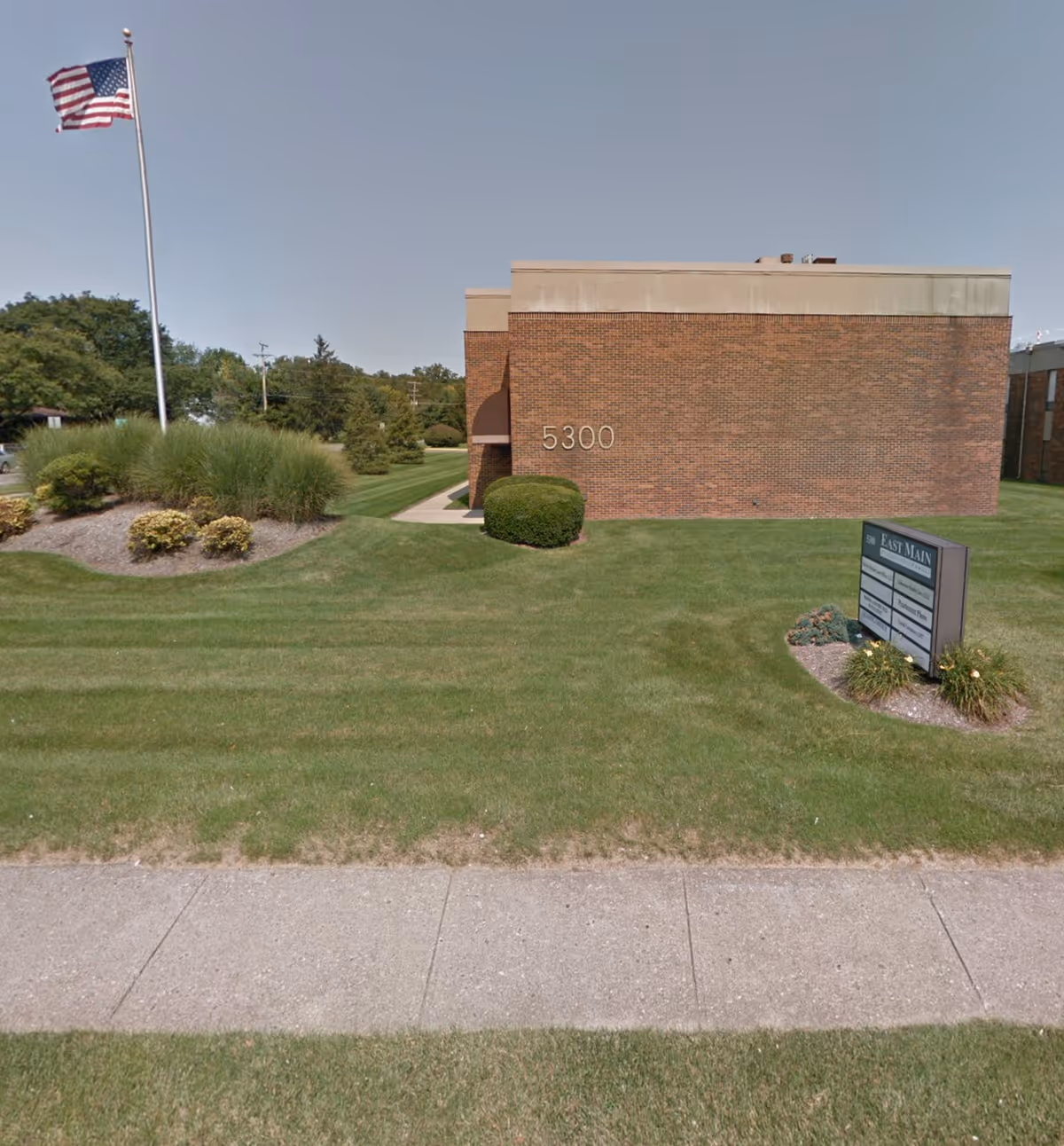 Brick building exterior with address 5300, flagpole, and manicured lawn in front.