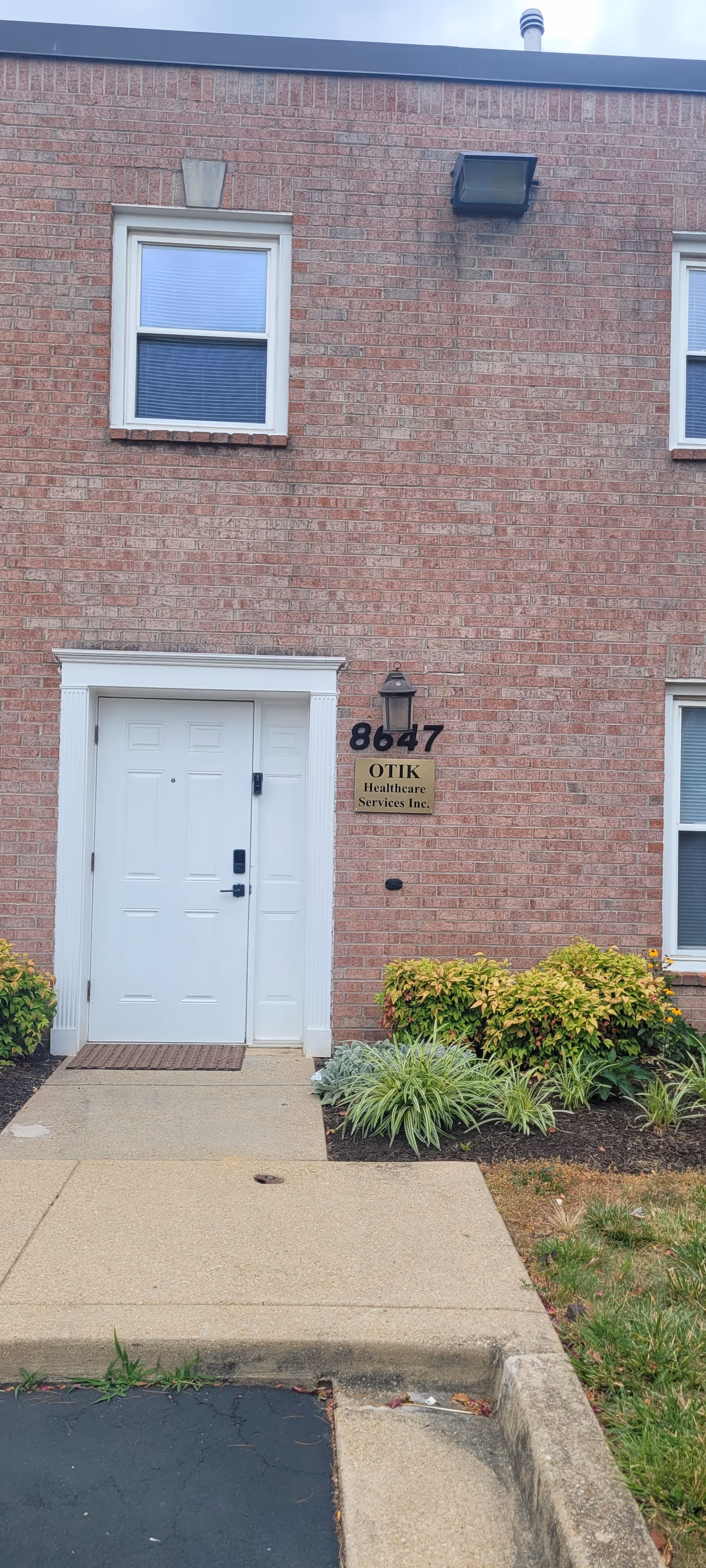 Brick building exterior featuring white entry door and OTIK Healthcare Services sign.